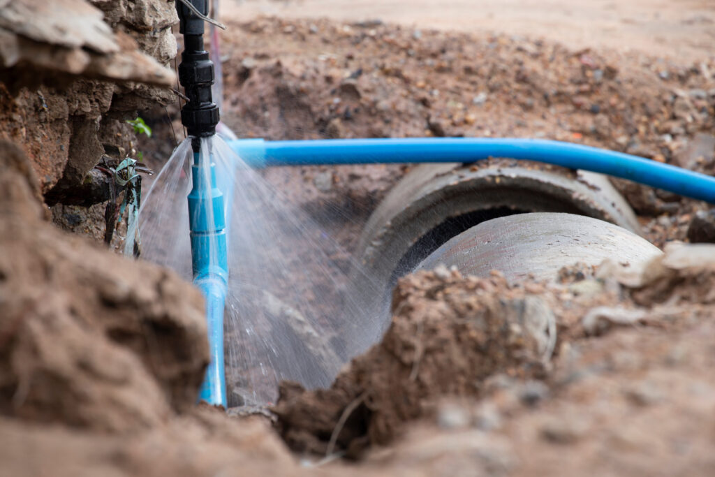 Water pipe break . Exposing a burst water main, focused on the spraying water and the pipe.