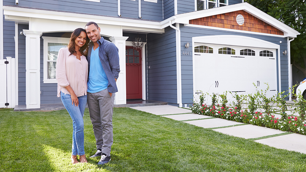 A family smiling outside their house